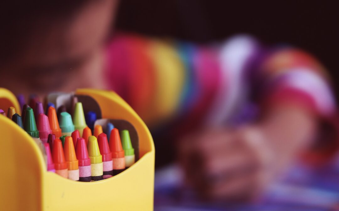 A child colors using crayons