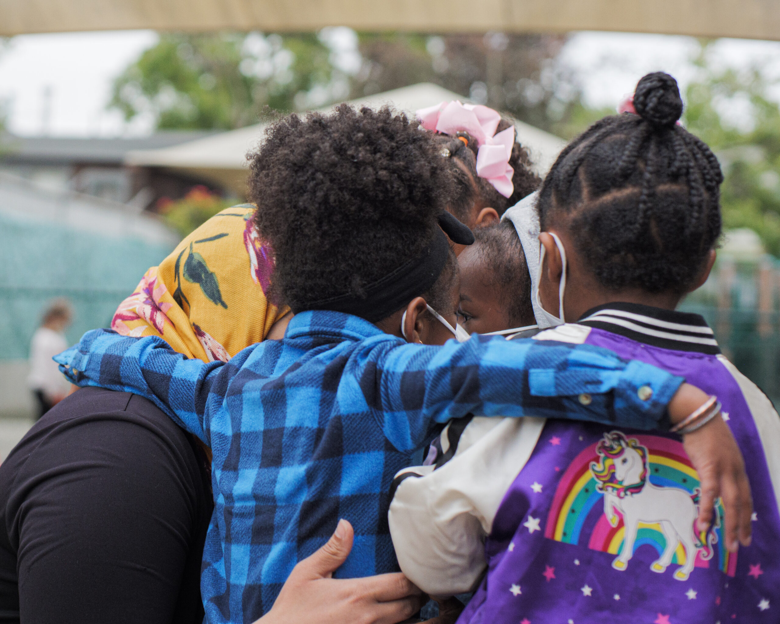 Two African American children huddle together with an adult wearing a head covering
